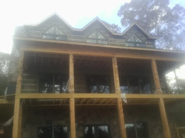 Dormers and porch framing on a large log home under construction — Roof Coating work by our crew in Etters