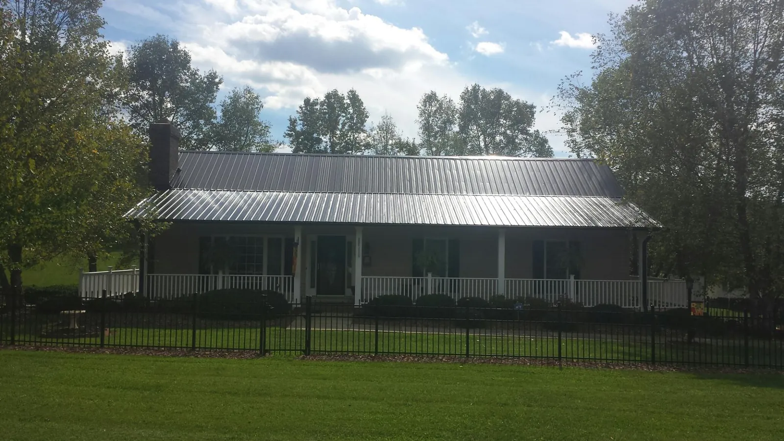 Gray metal roof on a brick ranch with a full width front porch — Gutter Guard Installation work by our crew in Etters