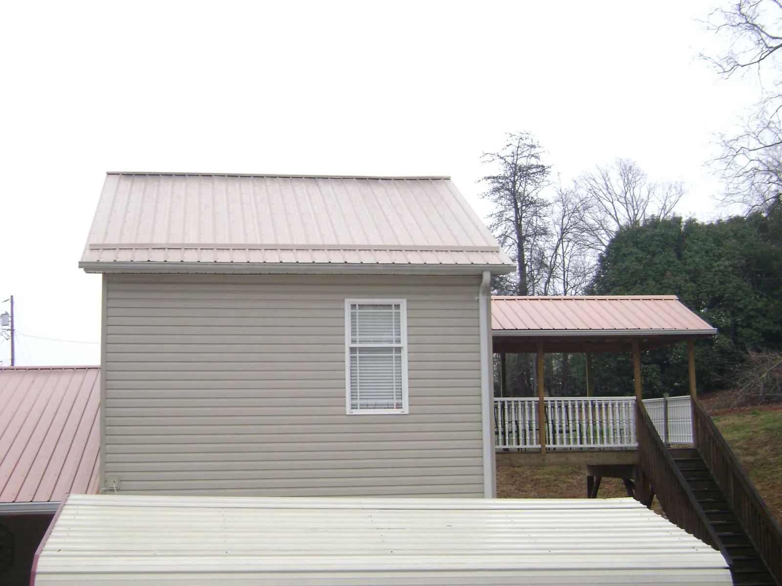 Tan metal roofs on a two story addition and attached porch, from a Roof Replacement job in Etters