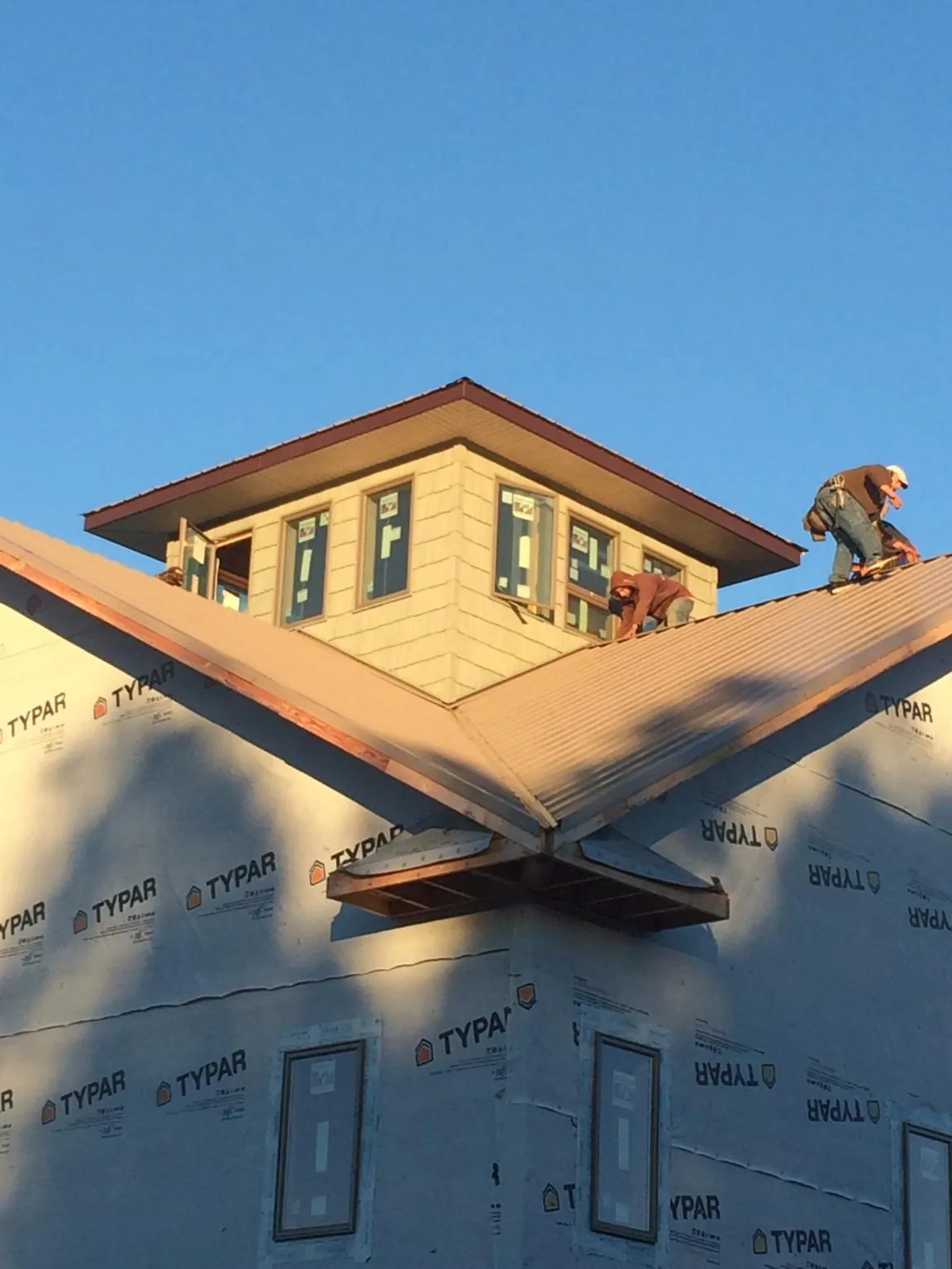 Roofers working around a rooftop cupola on a new metal roof at sunset — Roof Waterproofing in Etters by Roofing Brothers
